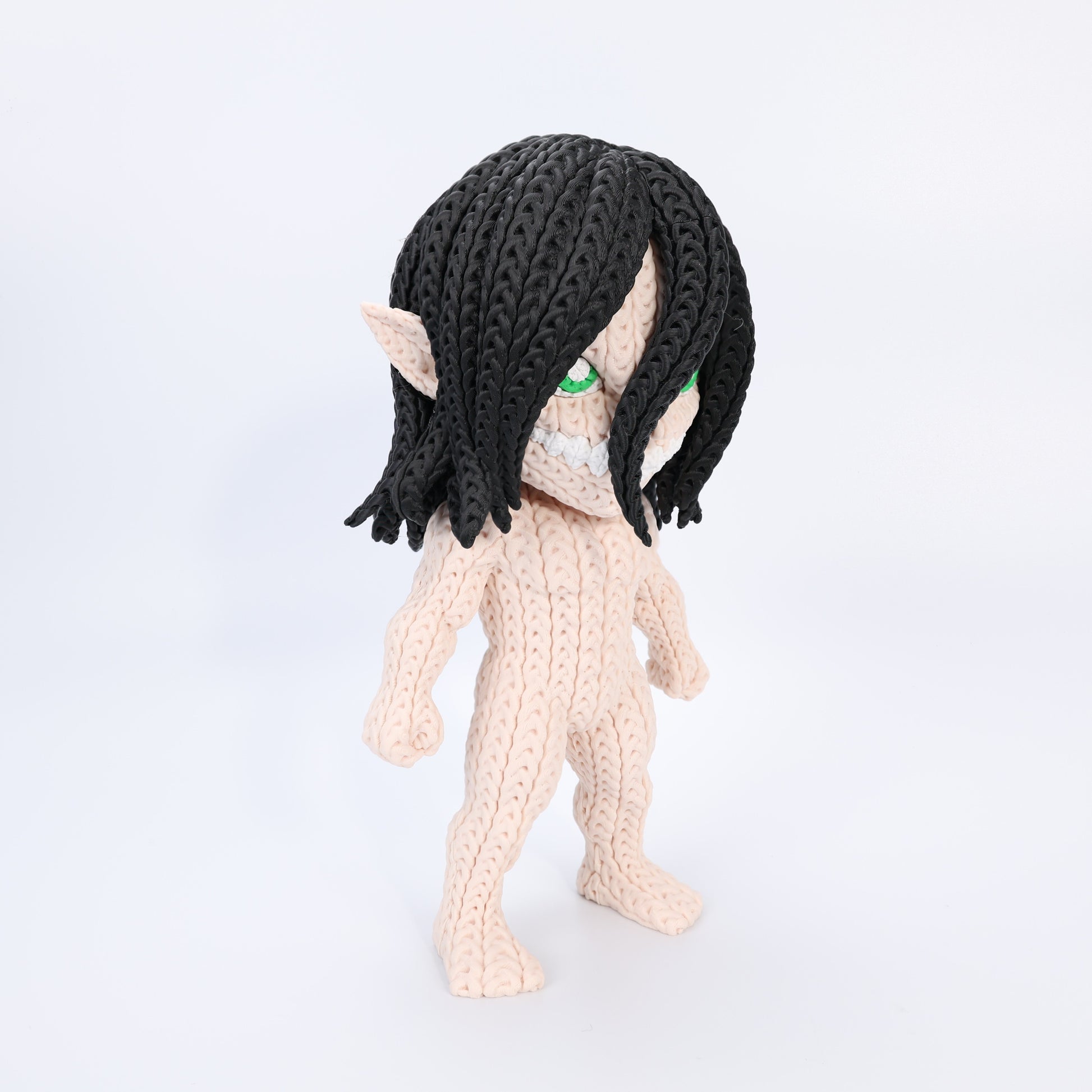 Crocheted textured figure with black hair and pointed ears on a white background